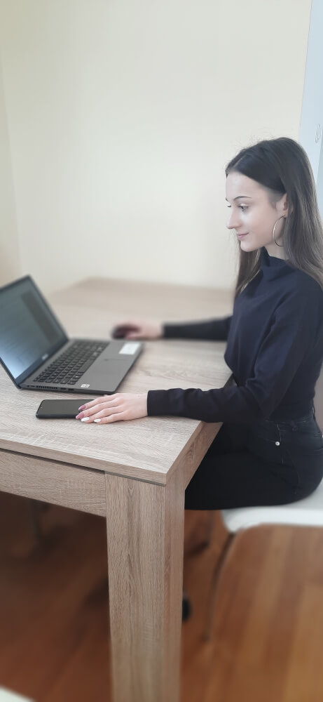Kobieta siedząca przy komputerze bez okularów korekcyjnych.